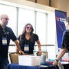 Attendee talking to sponsor representatives at their booth.