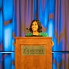 Conference emcee speaking at the podium.