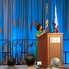 Conference emcee speaking at the podium.