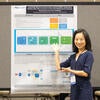 Poster presenter smiling with their poster.